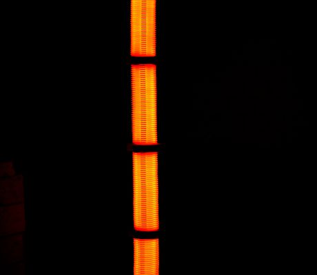 A vibrant orange tower light illuminating the darkness, reflected below, creating a striking vertical symmetry.
