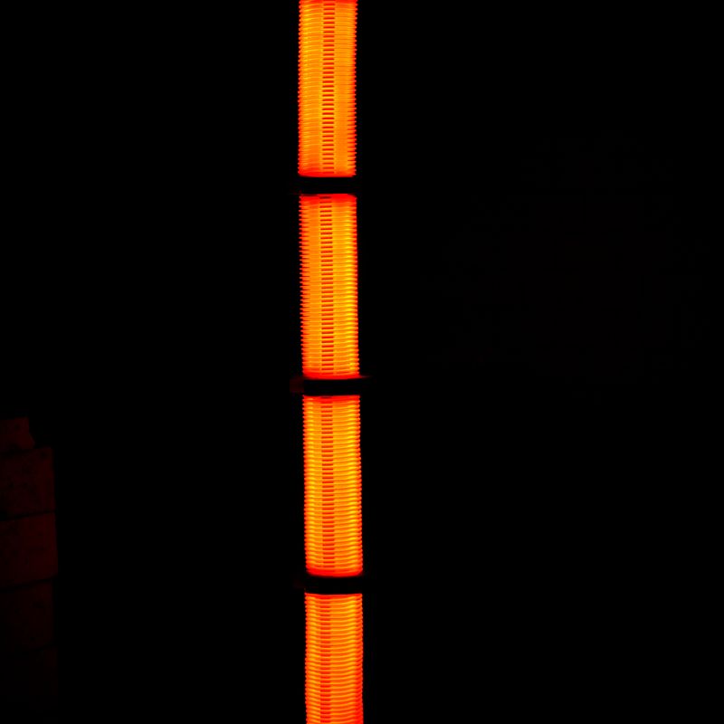 A vibrant orange tower light illuminating the darkness, reflected below, creating a striking vertical symmetry.