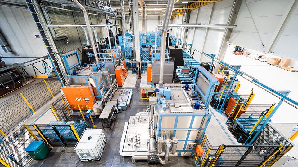 Aerial view of a modern industrial facility with various machinery, workstations, and equipment, enclosed by safety barriers.