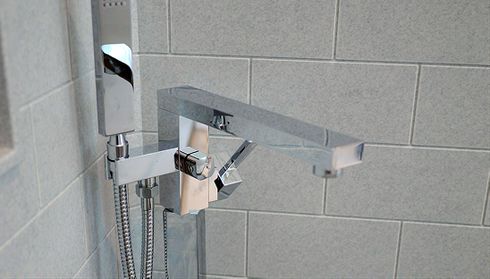 A modern chrome bathtub faucet with a matching hand shower