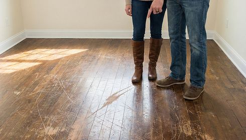 Couple pointing at scratched hardwood floor damage