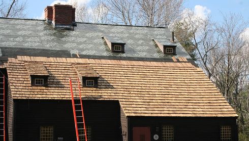 House roof under renovation with partially installed cedar shingles