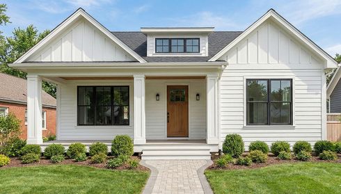 White fiber-cement siding on a house facade with black-framed windows and landscaped front yard