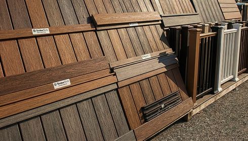 Display of various wood and composite decking samples in different shades of brown and gray