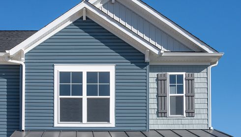 Blue fiber-cement siding with white trim around windows on a house gable