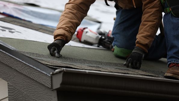 Roofer installing asphalt shingles during a roof replacement project