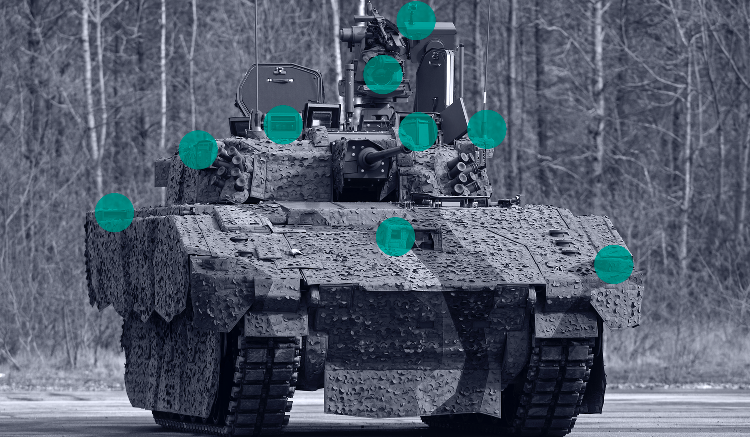 Military AJAX vehicle with camouflage, marked with green circles highlighting sensor features, parked on a road with trees in the background.