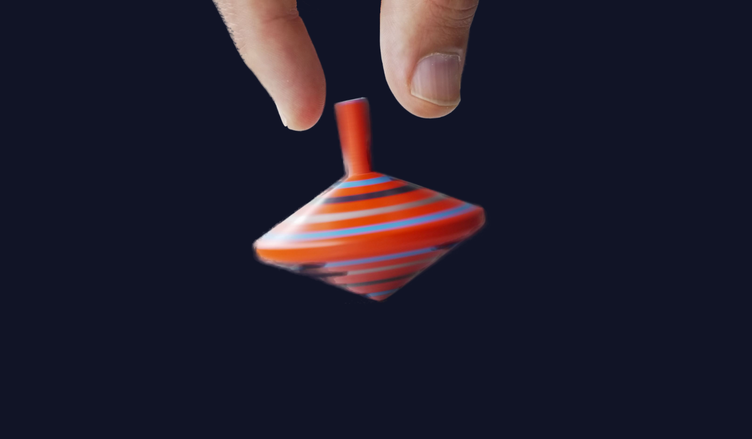 A hand releasing a spinning red and blue striped top against a dark background.
