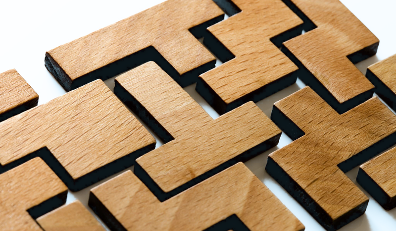 Wooden puzzle pieces with interlocking geometric shapes, arranged on a white surface.