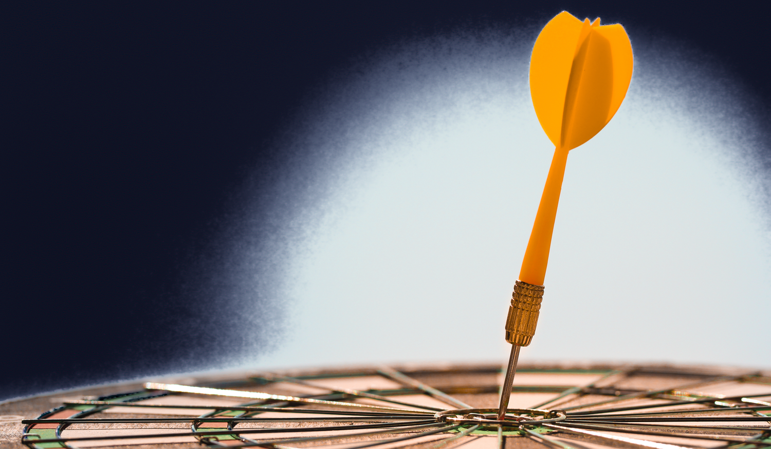 A yellow dart is perfectly lodged in the bullseye of a dartboard, set against a dark gradient background.