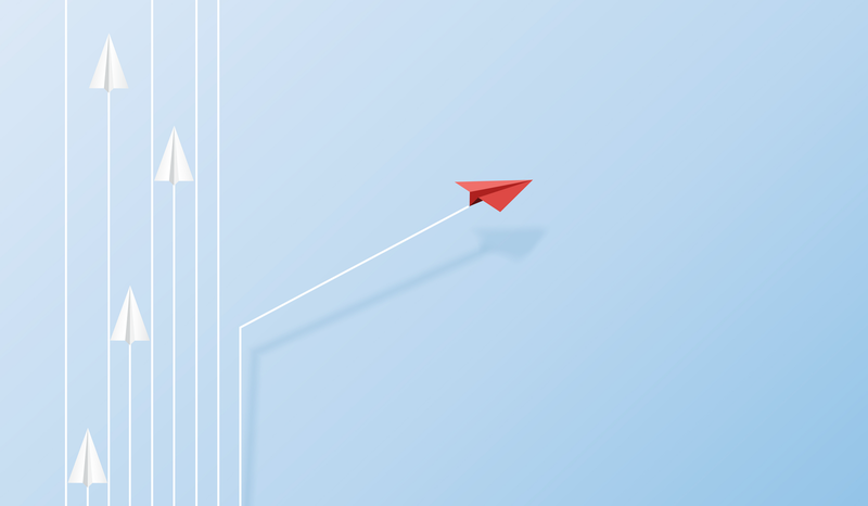 Red paper plane diverges from a group of white planes, symbolizing innovation and leadership, on a light blue background.
