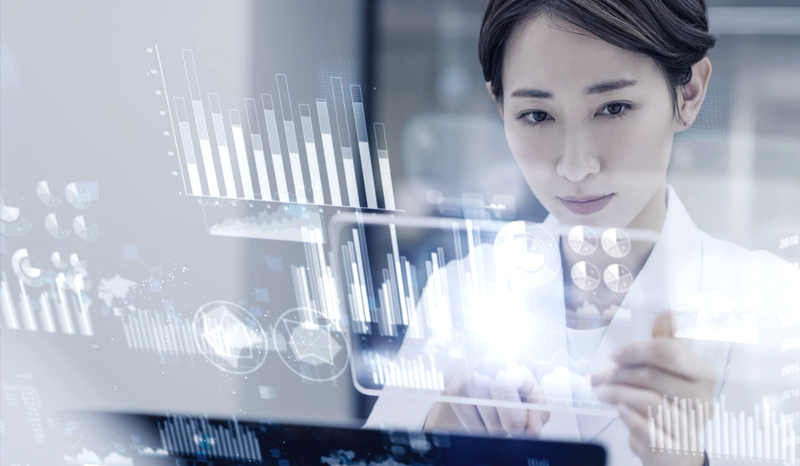 A person interacts with digital graphs and charts on a transparent screen, suggesting data analysis or futuristic technology.