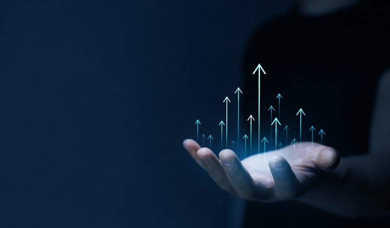 A person holds a glowing hologram of upward-pointing arrows, symbolizing growth and progress, against a dark background.