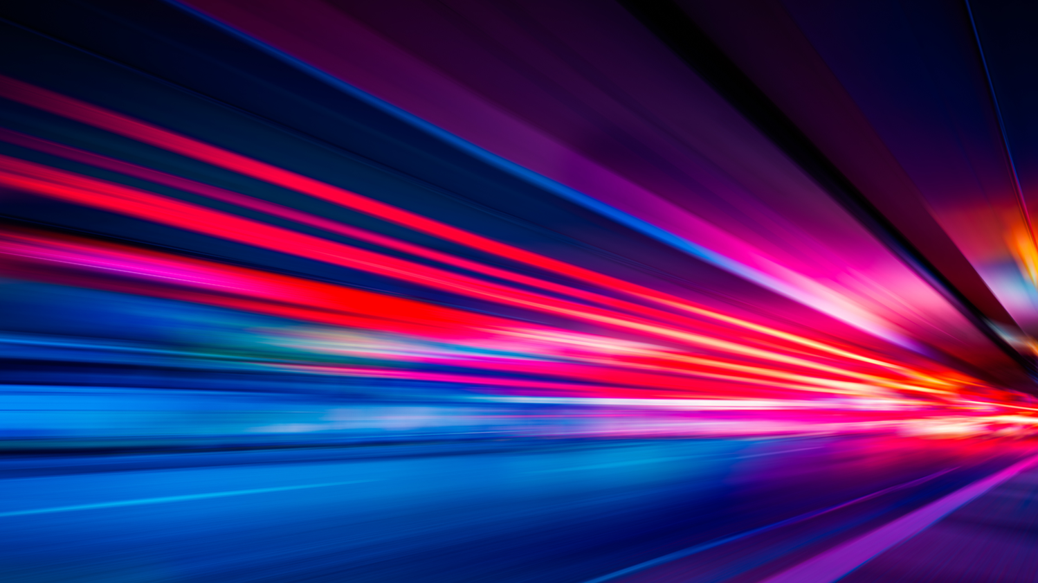 Abstract image of vibrant red, pink, and blue light streaks creating a dynamic, futuristic motion effect against a dark background.