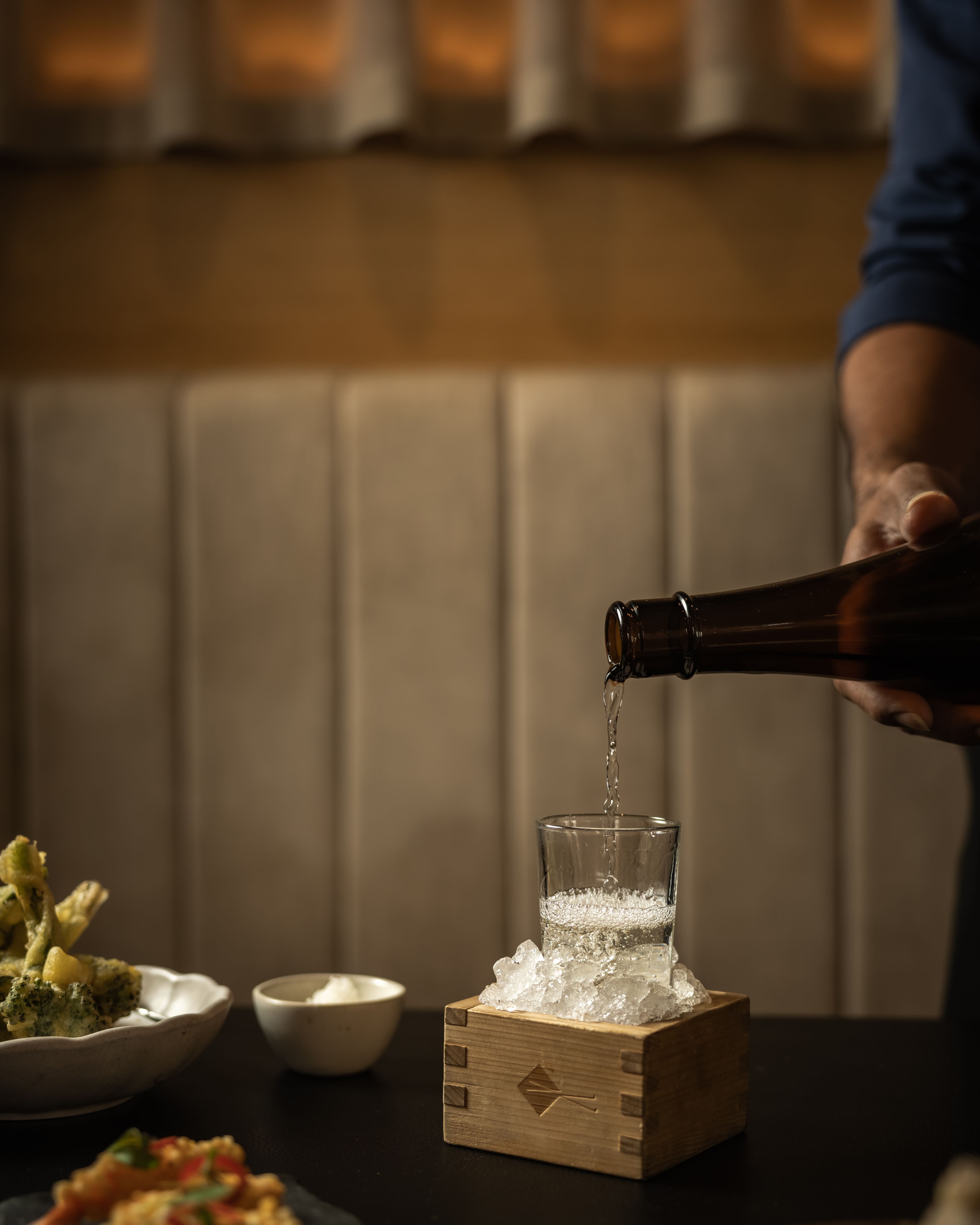 Sake hand pouring into glas and sushi