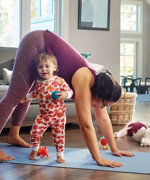 Frau macht Yoga und kleines Kind spielt daneben