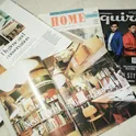 A spread of magazines featuring home decor articles and a men’s fashion cover, displayed on a flat surface.