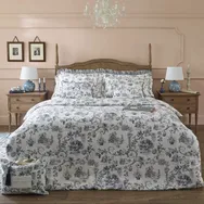 Elegant bedroom with a floral-patterned bedspread, wooden bedframe, two nightstands with lamps, and a chandelier above.