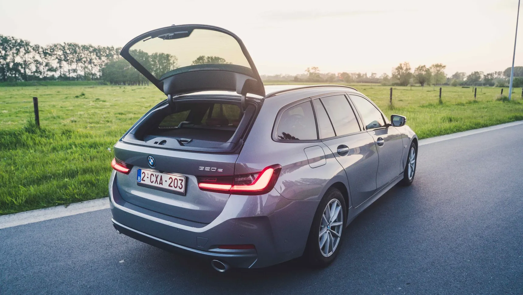 2024 BMW 320e Touring rear window open trunk sunset grass fields