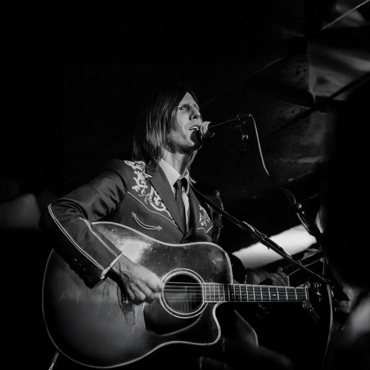 Steve Parkinson playing acoustic guitar and singing into a mic