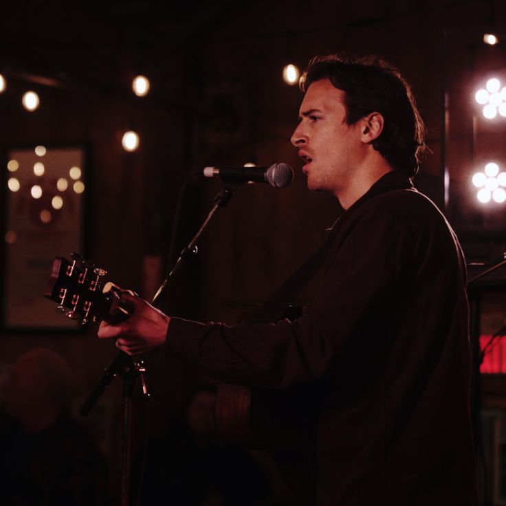 Nic Nolet singing into a mic with guitar