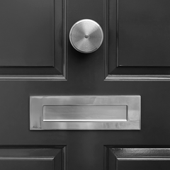 A black door features a round doorknob above a rectangular letterbox,