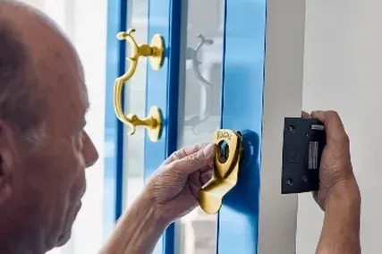 Engineer installing a brass door handle on a blue door.