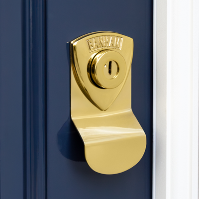 Banham door lock with a reflective surface, mounted on a dark blue door next to a white frame.