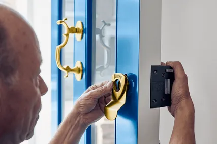 Engineer installing a brass lock on a blue door.