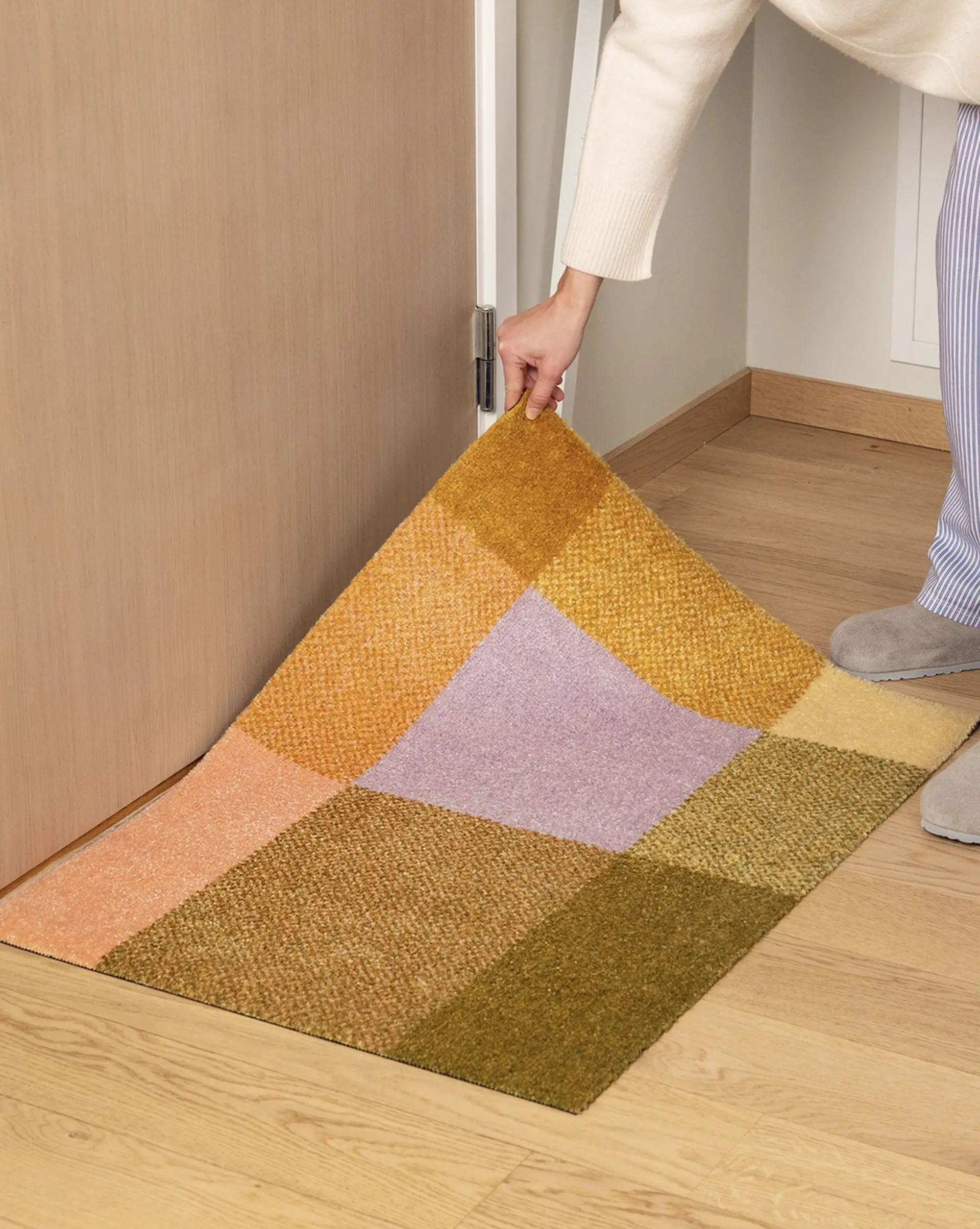 Person holding up a Heymat Mix Teklan indoor doormat