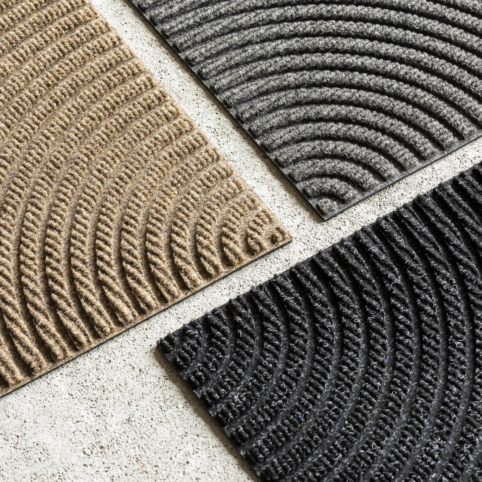 Heymat Zen tile samples in beige, grey and black on a light stone surface.