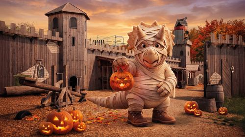 IKUNO als Mumie in der Piratenwelt zu Halloween IKUNO Dinosaurier als Mumie verkleidet mit leuchtender Kürbislaterne in der Piratenwelt des IKUNA Naturerlebnisparks bei Sonnenuntergang.