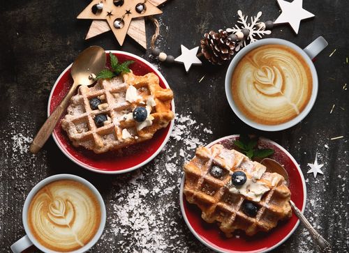Warme Waffeln und Cappucino am weihnachtlichen Frühstückstisch