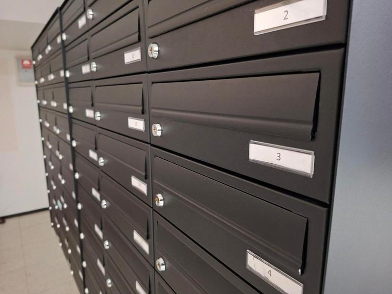 Nainen laittaa kirjettä postilokeroon – Cityvaraston vuokrattavat postilokerot