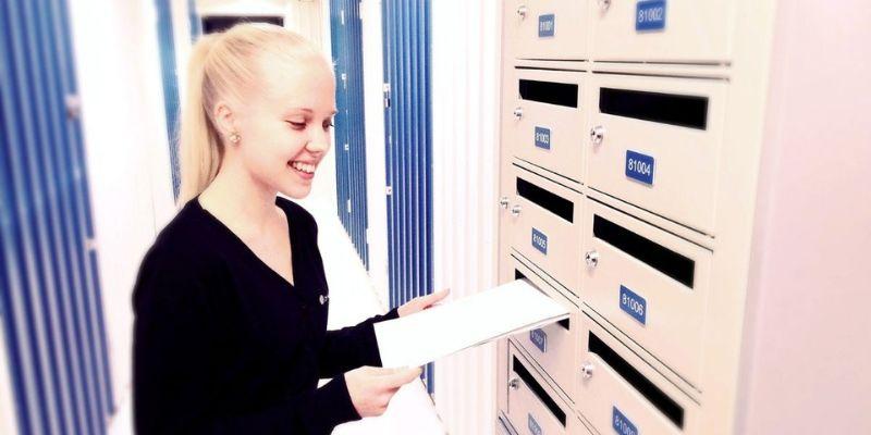 Woman putting mail into a Cityvarasto PO box available for rent