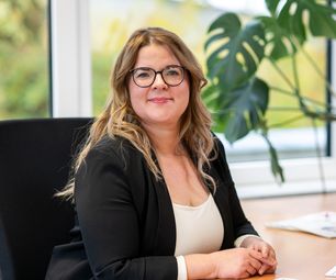 Mitarbeiterin der bauXpert Zentrale im Büro am Schreibtisch mit Computermaus und Unterlagen