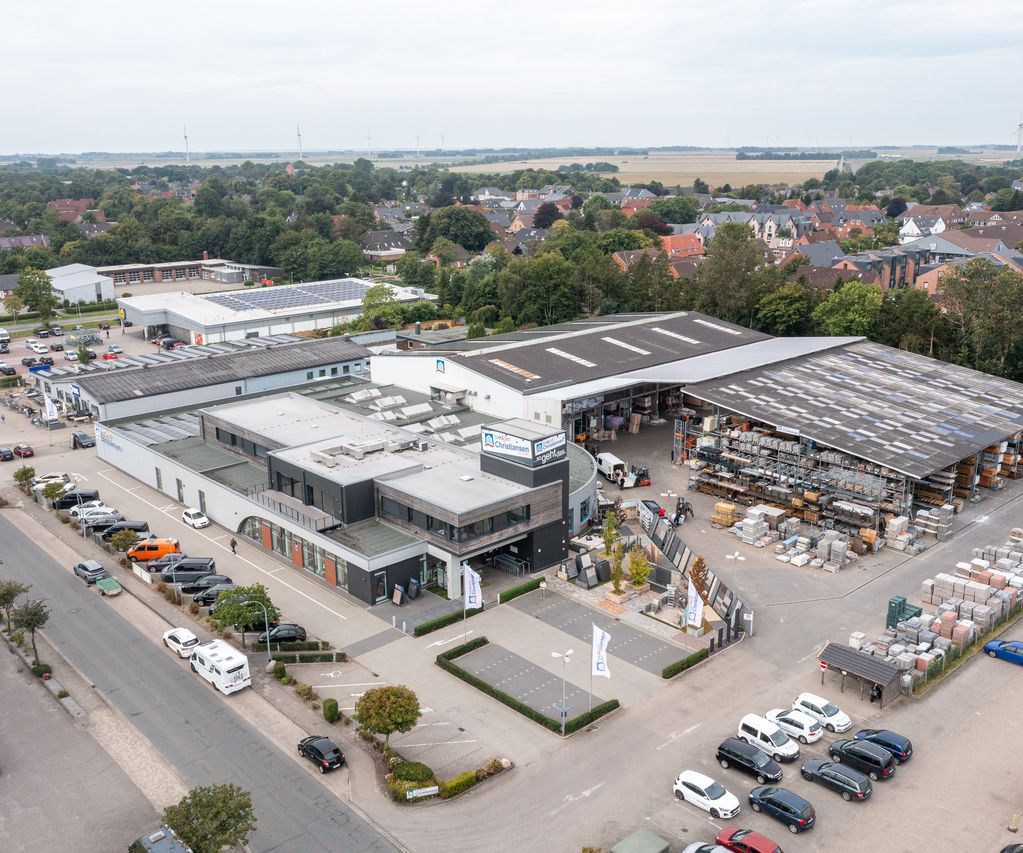 Luftaufnahme vom bauXpert Christiansen Standort mit Fachmarkt, Lagerhallen, Außenlager und Parkplatz