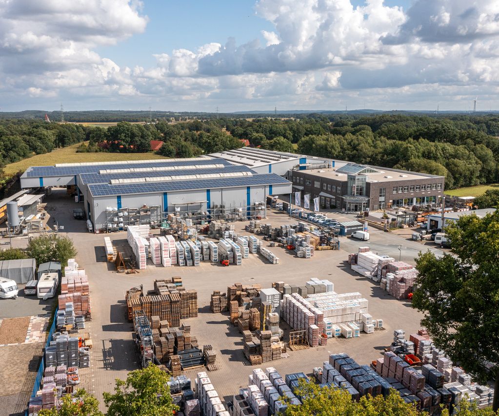 Luftaufnahme vom bauXpert Standort mit Lagerhallen, Außenlager und Baustoff-Paletten auf dem Hof