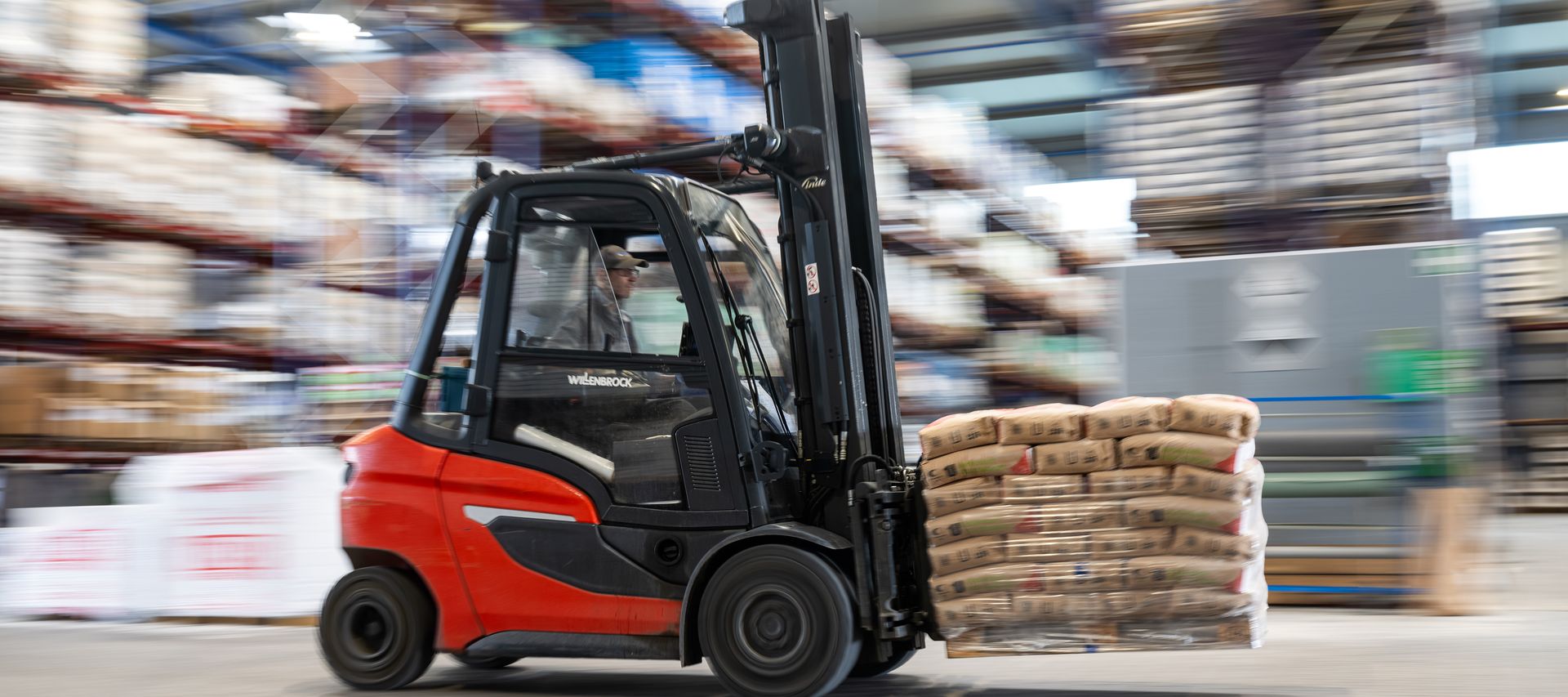 Gabelstapler transportiert palettierte Sackware durch das Lager im Baustoffhandel