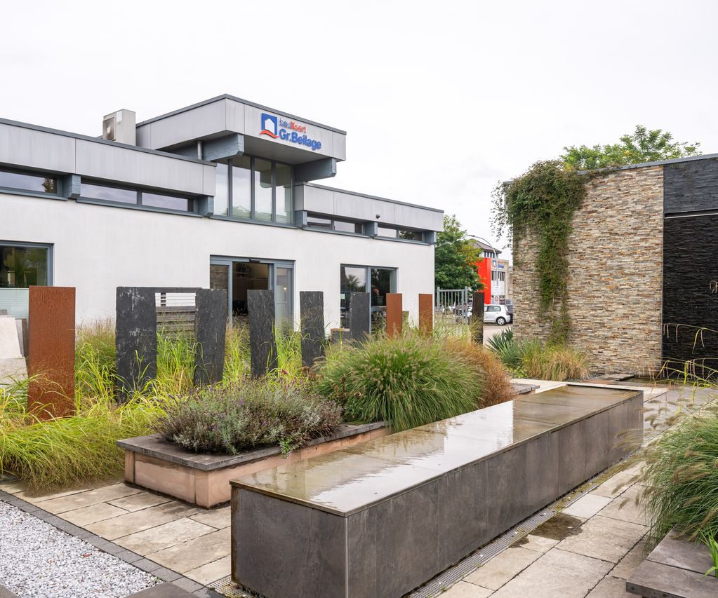 Außenbereich bei bauXpert Gr.Beilage mit Pflanzbeeten, Musterstelen und Wasserwand aus Naturstein