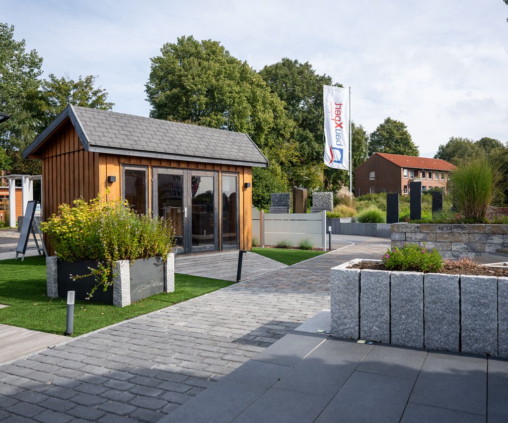 Garten-Ausstellung bei bauXpert Dittmer mit Musterflächen, Pflasterweg und Holz-Gartenhaus