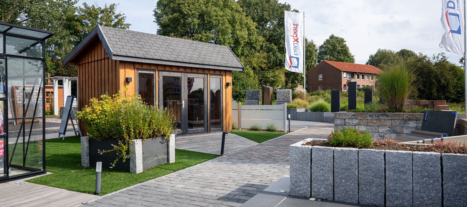 Garten-Ausstellung bei bauXpert Dittmer mit Musterflächen, Pflasterweg und Holz-Gartenhaus