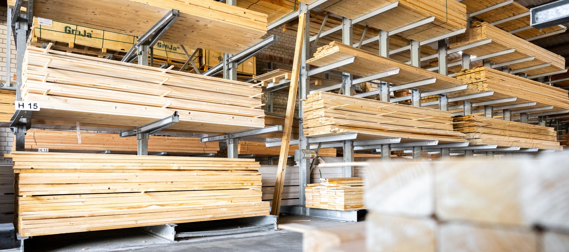 Holzlager mit Konstruktionsholz und Brettern im Regal im Baustoffhandel