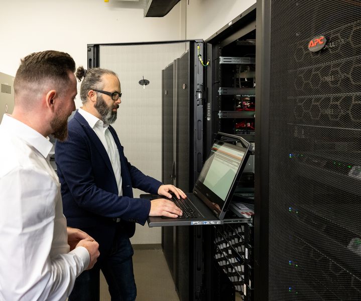IT-Mitarbeiter der bauXpert Zentrale bei Systemprüfung im Serverraum der Systemzentrale