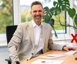 Mitarbeiter der bauXpert Zentrale im Büro am Schreibtisch mit Monitor und Tastatur