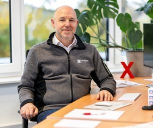 Mitarbeiter der bauXpert Zentrale im Büro am Schreibtisch mit Monitor und Tastatur