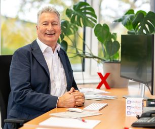 Mitarbeiter Xpert Direkt der bauXpert Zentrale im Büro am Schreibtisch mit Monitor und Unterlagen