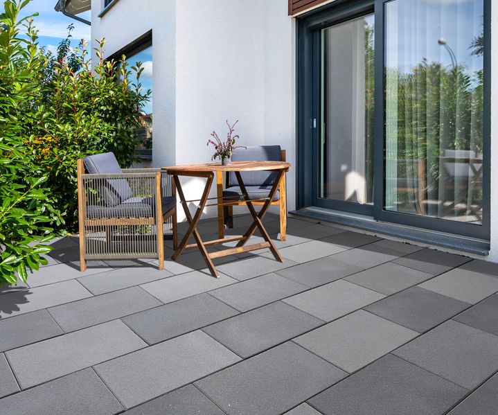 Eine Gartenmöbelgruppe mit Tisch und Stühlen steht auf der Terrasse und lädt zum Verweilen ein.