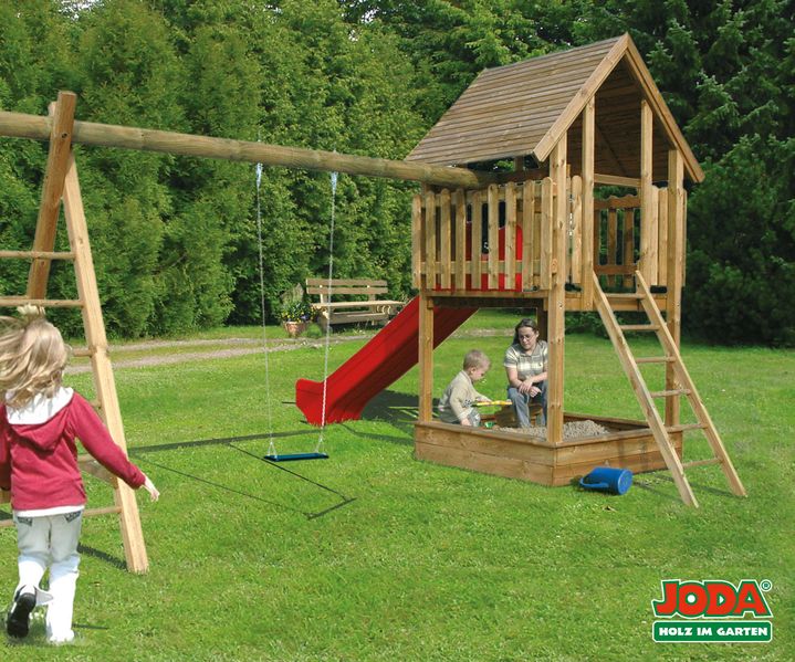 Ein Spielgerät mit Rutsche und Kletterelementen steht auf einer Rasenfläche im Garten.