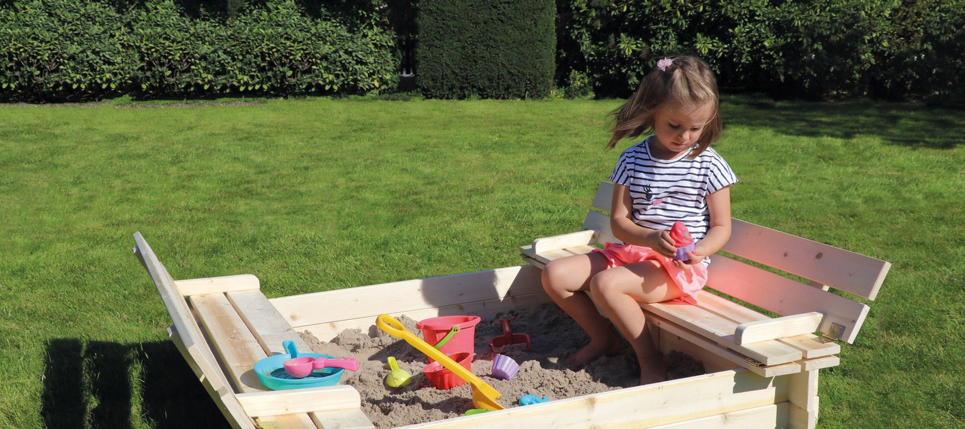 Eine Sandkiste aus Holz kombiniert Klettern, Rutschen und Verstecken im eigenen Garten.